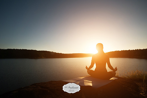 Silhouette of healthy woman is practicing yoga at mountain lake